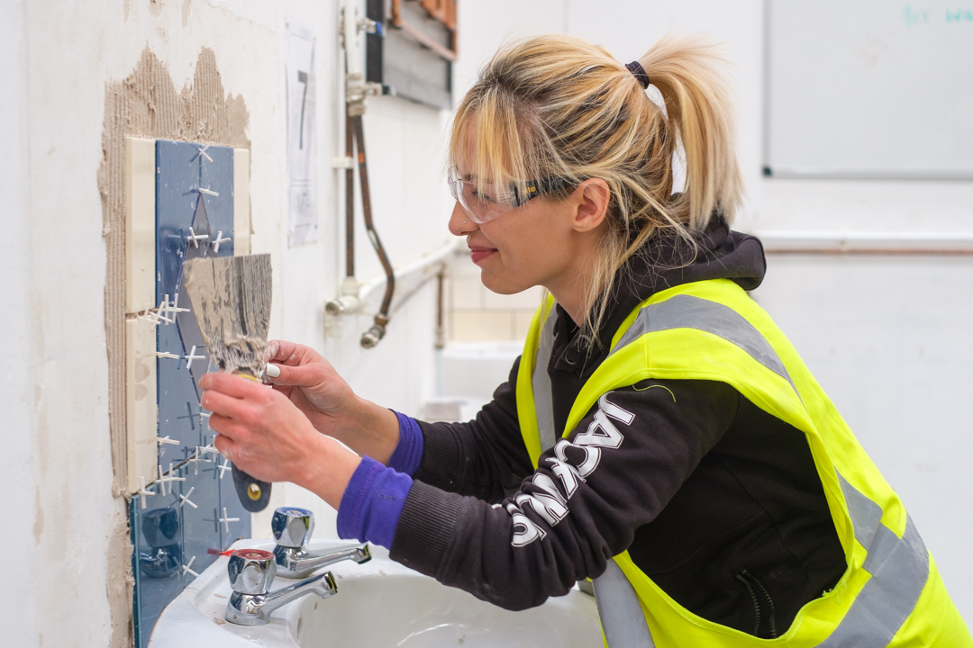 woman tiler being trained at The STC Group in Essex, construction training for women in Harold Wood and London, what is retrofit